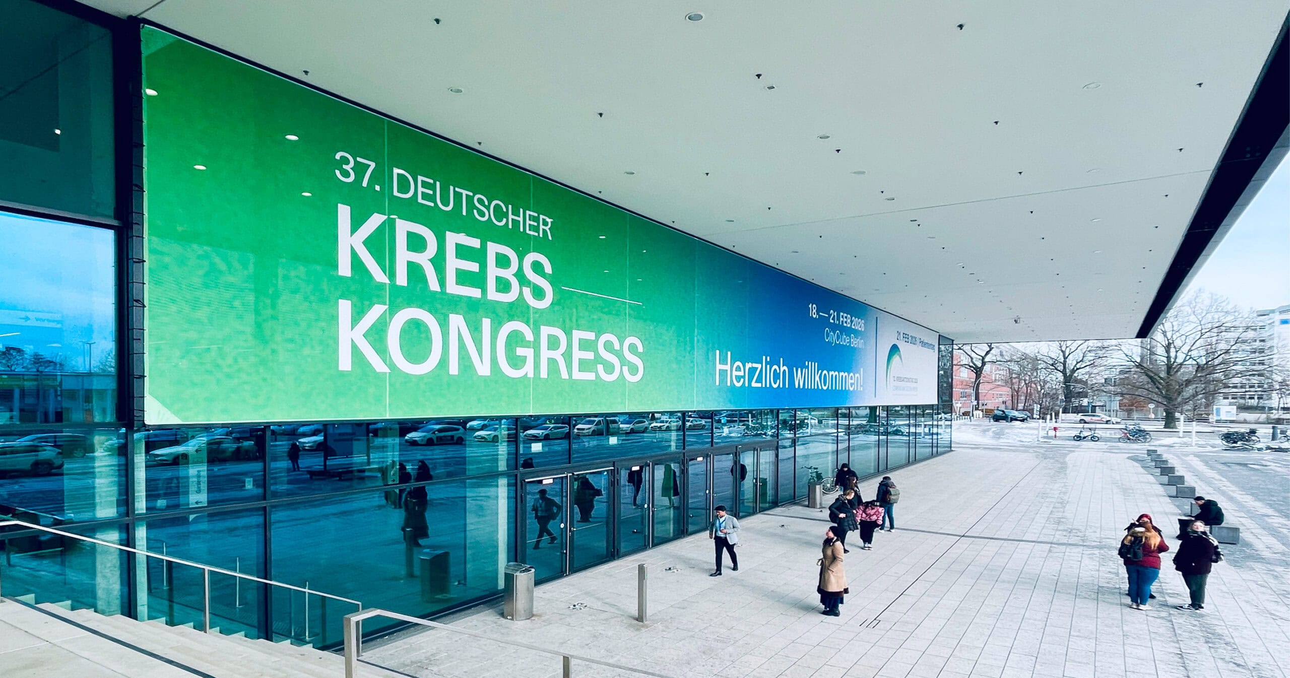 Großflächiges Banner des 37. Deutscher Krebskongresses an der Fassade des CityCube Berlin mit Willkommensbotschaft.
