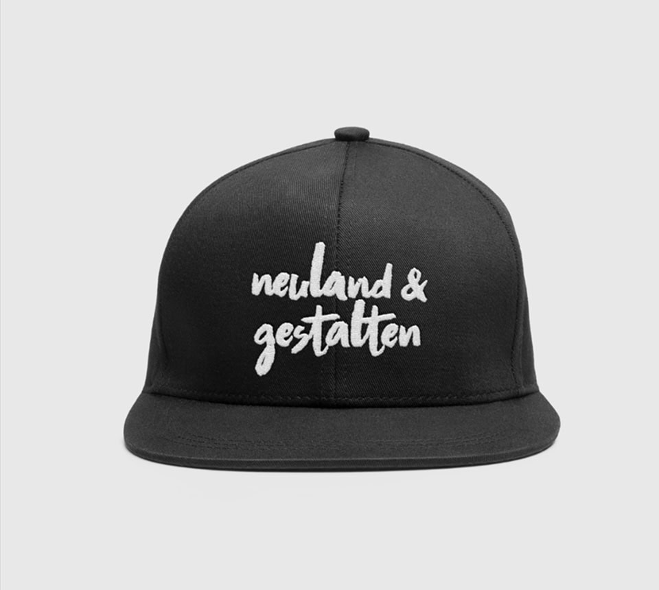 Schwarze Cap mit aufgesticktem Logo von neuland gestalten.