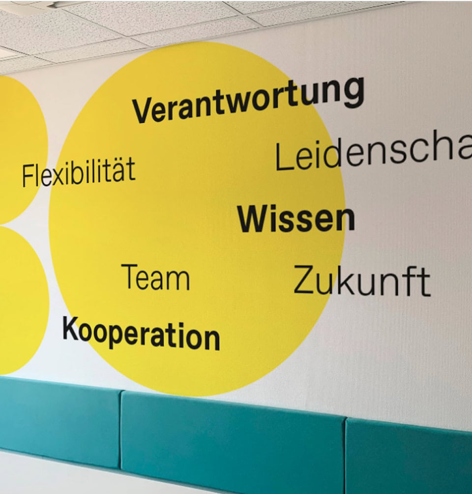 Wandgestaltung mit Unternehmenswerten wie Verantwortung, Wissen und Kooperation im Corporate Design.