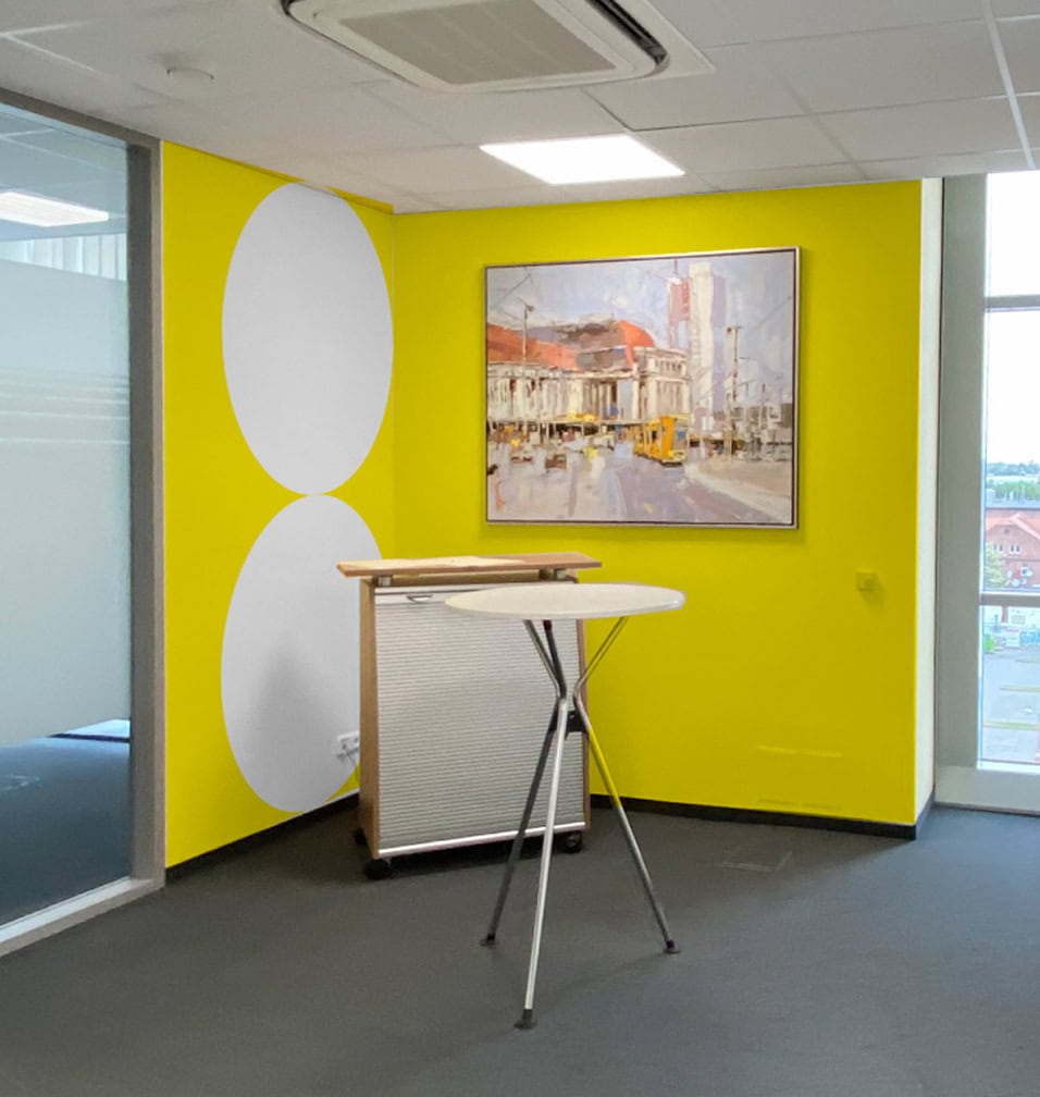 Besprechungsbereich mit gelber Wandgestaltung und grafischen Kreiselementen im Corporate Design.